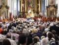 Priester, Banner und Gemeinde umsteht den Altar